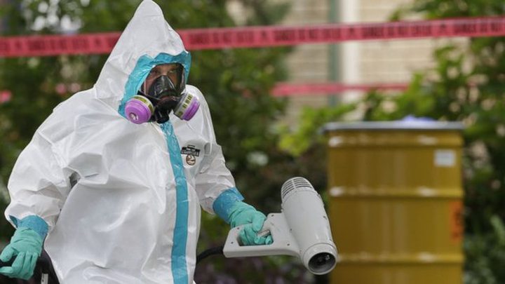 A hazmat worker clean outside the apartment building of a hospital worker, Sunday, Oct. 12, 2014