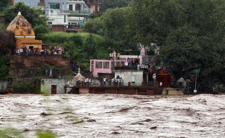 Residents watch the overflowing Chenab River after heavy rains at Akhnoor, in Jammu and Kashmir