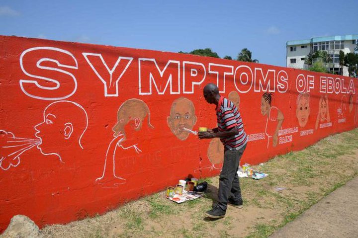 Stephen Doe, paints an educational mural to inform people about the symptoms of the deadly Ebola