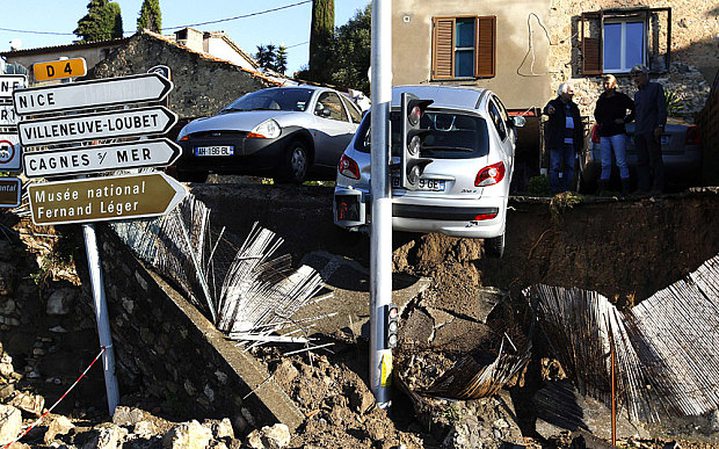 A boy stands next to rubble and damaged cars after violent storms and floods in Biot