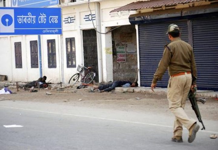 A policeman walks past injured tribal demonstrators after a clash during a protest at Dekiajuli town
