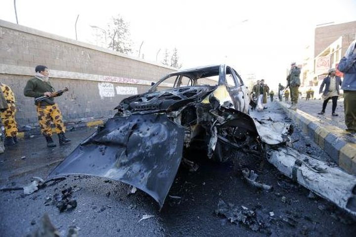 Policemen look at the wreckage of a car at the scene of a car bomb outside the police college 