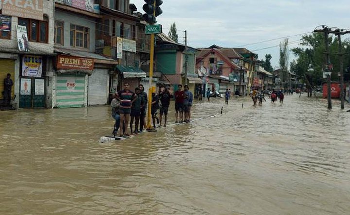 People make their way along a flooded street in Srinagar on September 9, 2014