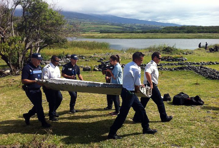Police officers carried a piece of debris that appeared to be an airplane part found on Réunion