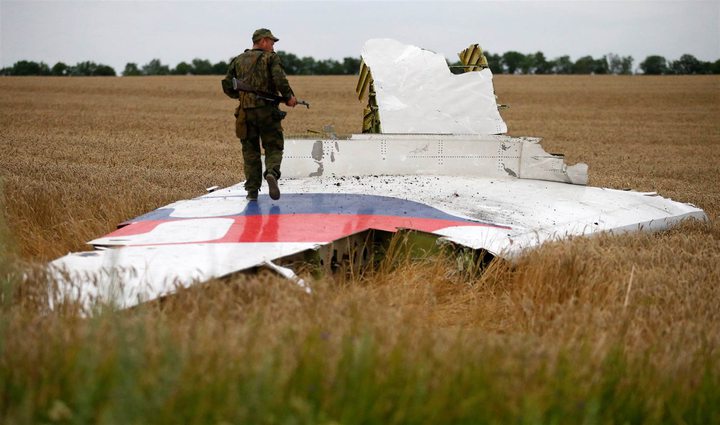 An armed pro-Russian separatist stands on part of the wreckage of MH17