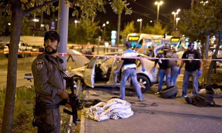 An Israeli policeman stands next to a car wreck in Jerusalem October 22, 2014