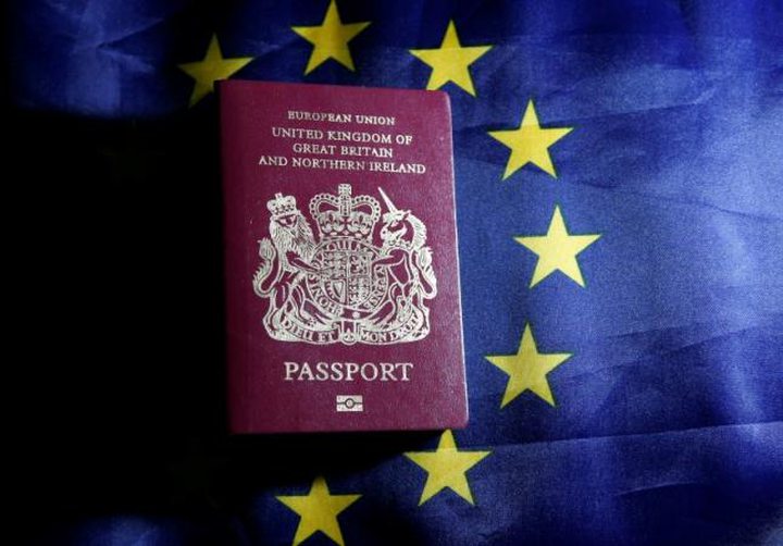 A British passport is pictured in front of an European Union flag
